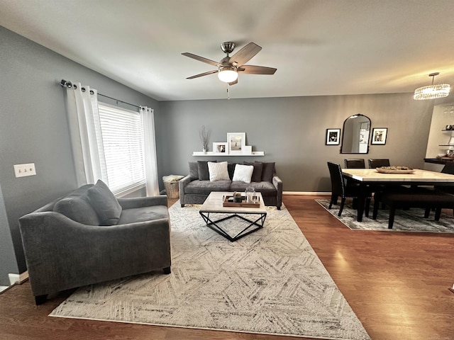 living area with dark wood finished floors, a ceiling fan, and baseboards