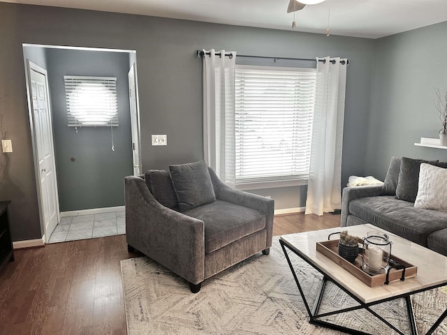 living area featuring a ceiling fan, wood finished floors, baseboards, and a wealth of natural light