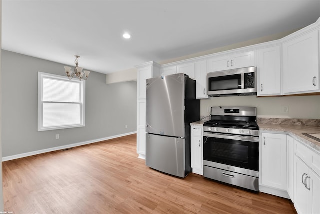 kitchen with white cabinetry, stainless steel appliances, an inviting chandelier, light wood finished floors, and baseboards