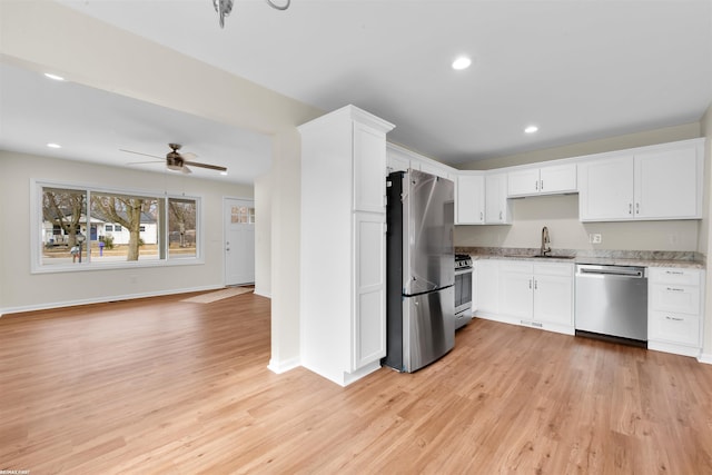 kitchen featuring white cabinets, appliances with stainless steel finishes, light wood-style floors, and a sink