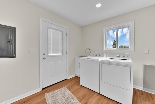 laundry room featuring washing machine and clothes dryer, cabinet space, baseboards, and light wood-style floors