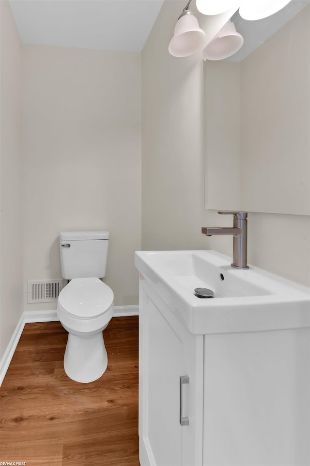 bathroom with visible vents, toilet, wood finished floors, baseboards, and vanity