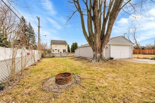 view of yard with a garage, an outbuilding, a fire pit, and a fenced backyard