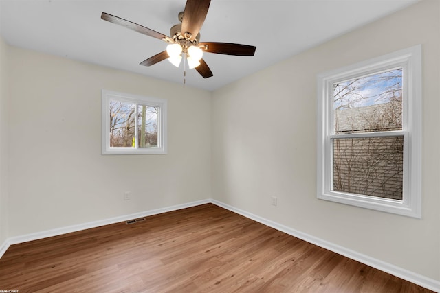 unfurnished room with light wood finished floors, visible vents, ceiling fan, and baseboards