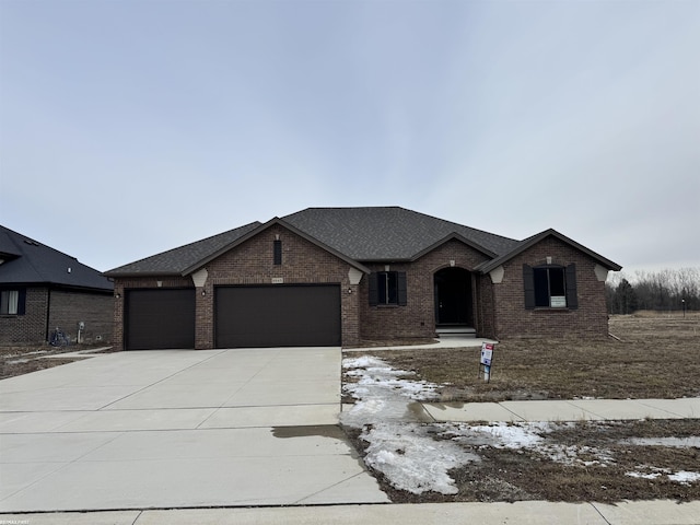 ranch-style home with brick siding, roof with shingles, concrete driveway, and an attached garage