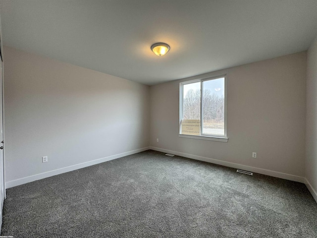 unfurnished room with visible vents, baseboards, and dark carpet