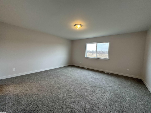 empty room with visible vents, baseboards, and dark colored carpet