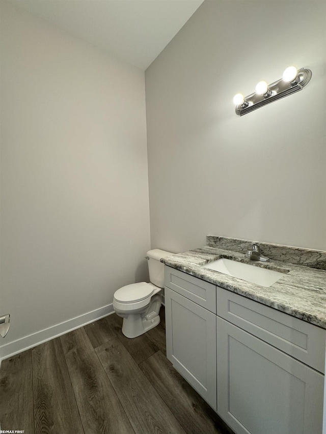 bathroom with baseboards, toilet, wood finished floors, and vanity