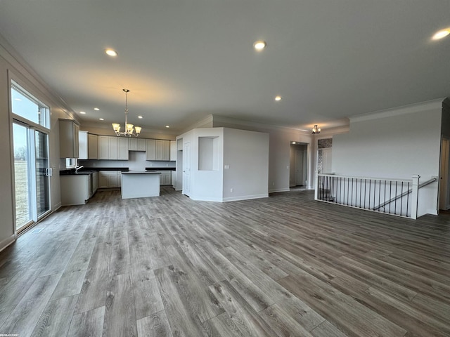 kitchen with a chandelier, dark countertops, open floor plan, and ornamental molding