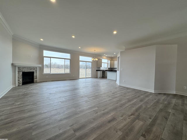 unfurnished living room with dark wood finished floors, a notable chandelier, crown molding, and baseboards