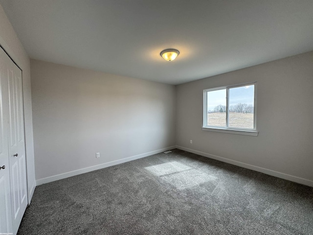 unfurnished bedroom featuring a closet, baseboards, and dark carpet