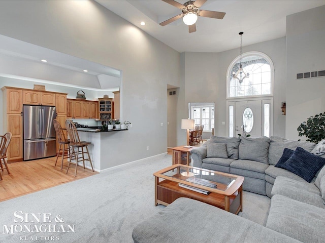 living area with visible vents, baseboards, light colored carpet, recessed lighting, and a high ceiling