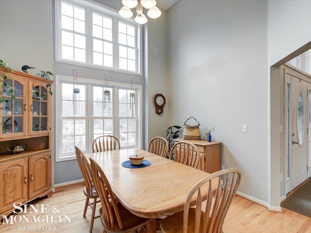 dining room featuring a healthy amount of sunlight, light wood-type flooring, and a high ceiling