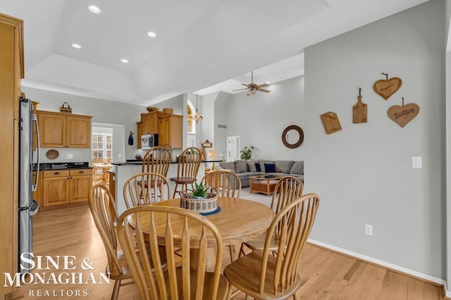 dining area with a raised ceiling, recessed lighting, light wood-style floors, baseboards, and ceiling fan