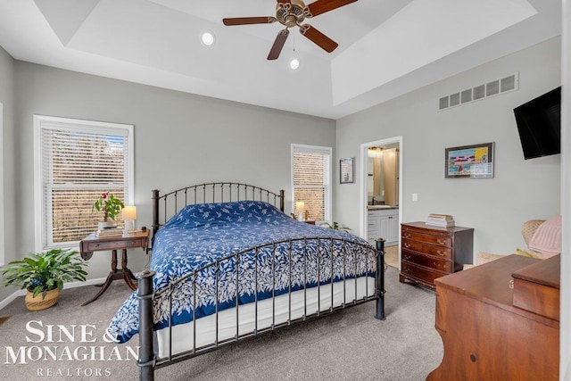 carpeted bedroom with a tray ceiling, visible vents, and multiple windows