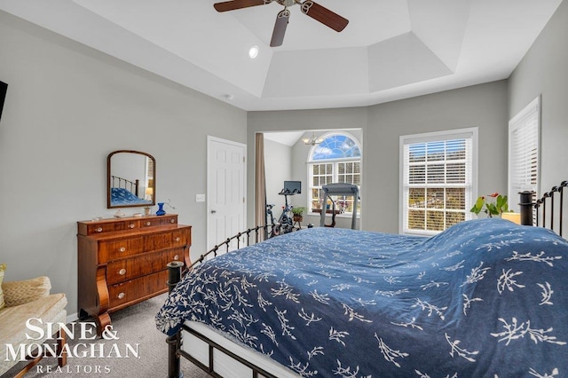 bedroom featuring a raised ceiling, carpet flooring, and ceiling fan with notable chandelier