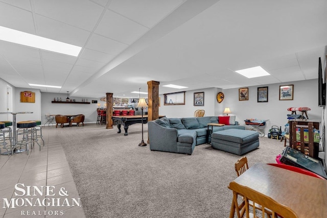 living room with tile patterned flooring, pool table, a paneled ceiling, and decorative columns