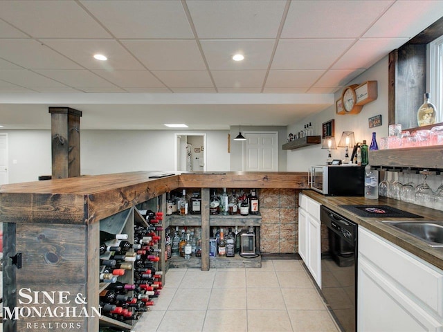 interior space with white cabinetry, light tile patterned flooring, a paneled ceiling, dishwasher, and dark countertops