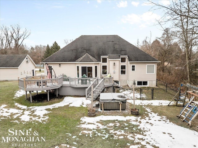 back of house with a shingled roof, a hot tub, a deck, and fence