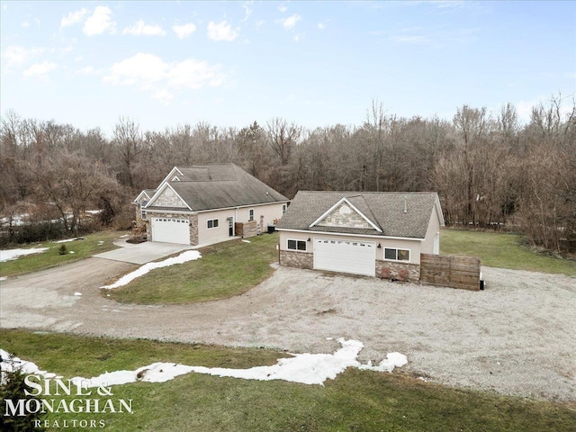 view of front of home featuring stone siding, a garage, and a front yard