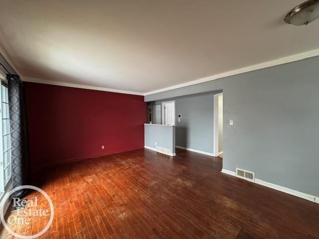 unfurnished room with visible vents, baseboards, wood finished floors, and ornamental molding