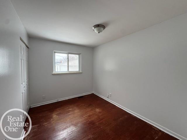 unfurnished bedroom with dark wood finished floors, baseboards, and a closet