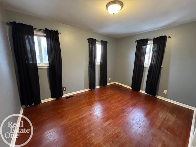 empty room featuring visible vents, baseboards, and wood finished floors