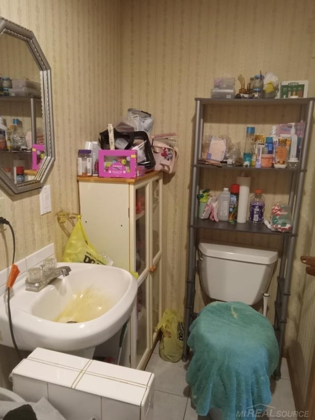 bathroom with wallpapered walls, tile patterned floors, toilet, and a sink