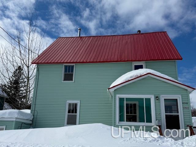 snow covered house featuring metal roof