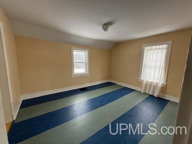 spare room with visible vents, baseboards, and vaulted ceiling