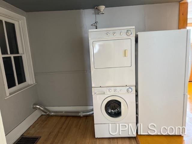 laundry room featuring stacked washer / dryer, laundry area, visible vents, and wood finished floors