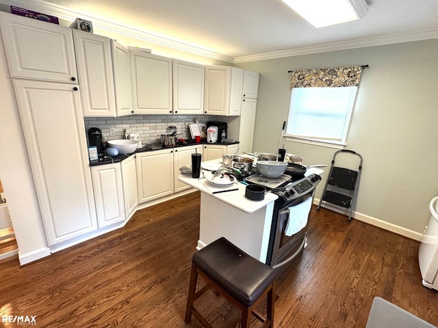 kitchen with dark countertops, decorative backsplash, ornamental molding, and dark wood-style flooring