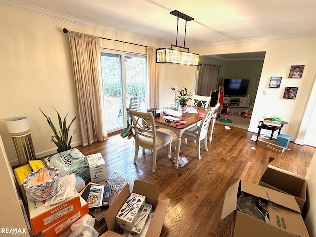 dining room featuring baseboards, wood finished floors, and ornamental molding