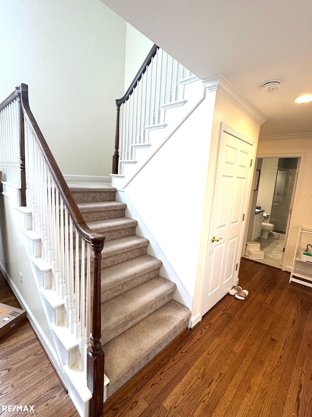 staircase with baseboards, wood finished floors, and crown molding