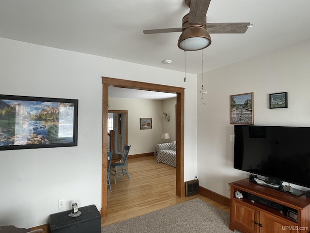 living area with light wood-style flooring, a ceiling fan, visible vents, and baseboards