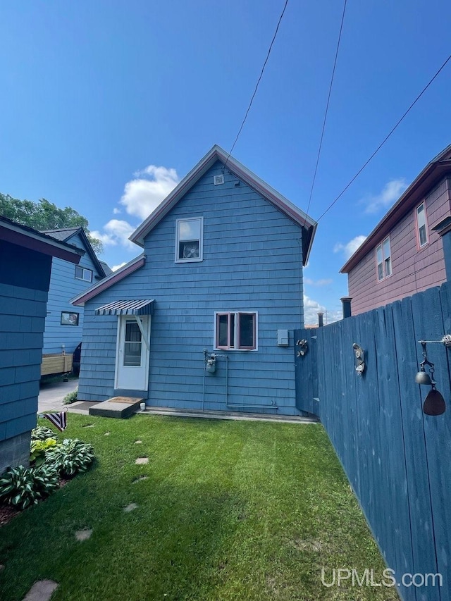 back of house with a lawn and fence