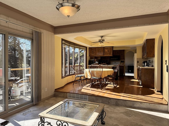 dining area featuring arched walkways, visible vents, a textured ceiling, and crown molding