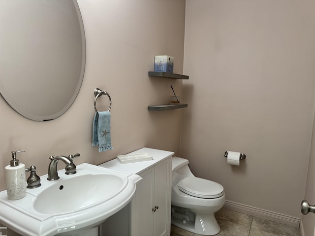 bathroom featuring tile patterned floors, toilet, baseboards, and a sink