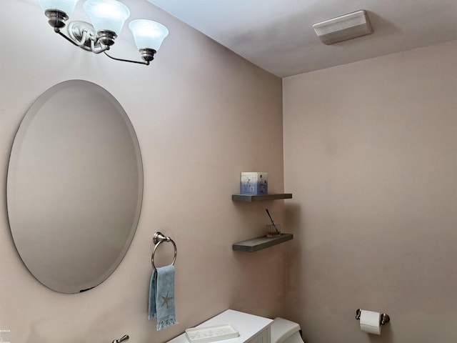 bathroom with a notable chandelier and toilet