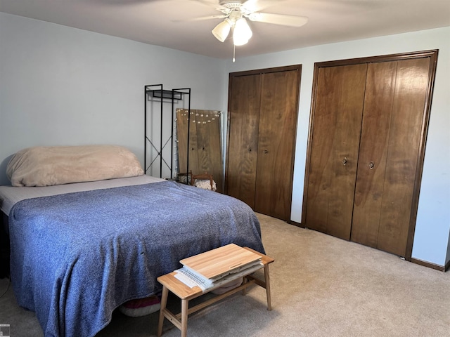 bedroom featuring carpet flooring, ceiling fan, and multiple closets