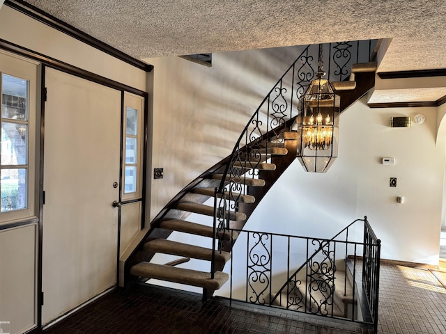 stairs with a notable chandelier, a textured ceiling, crown molding, and baseboards