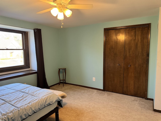 bedroom with a ceiling fan, baseboards, a closet, and light carpet