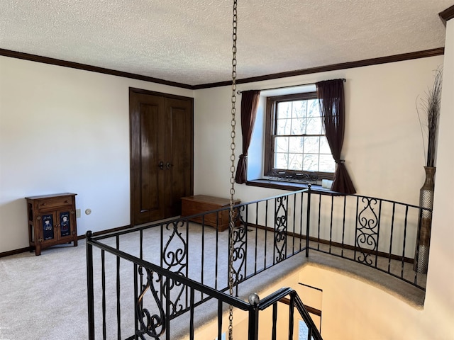 staircase featuring a textured ceiling, crown molding, baseboards, and carpet floors