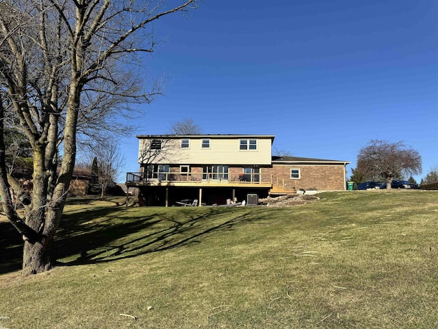 rear view of house with brick siding, a lawn, and a deck