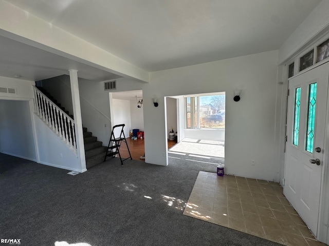 entryway with visible vents, stairs, and carpet floors