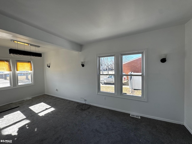 empty room featuring visible vents, dark carpet, and baseboards