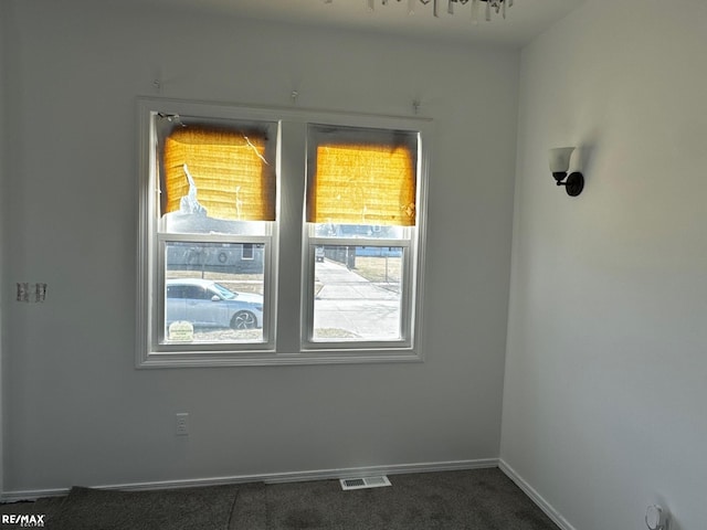 empty room with visible vents, baseboards, and dark colored carpet