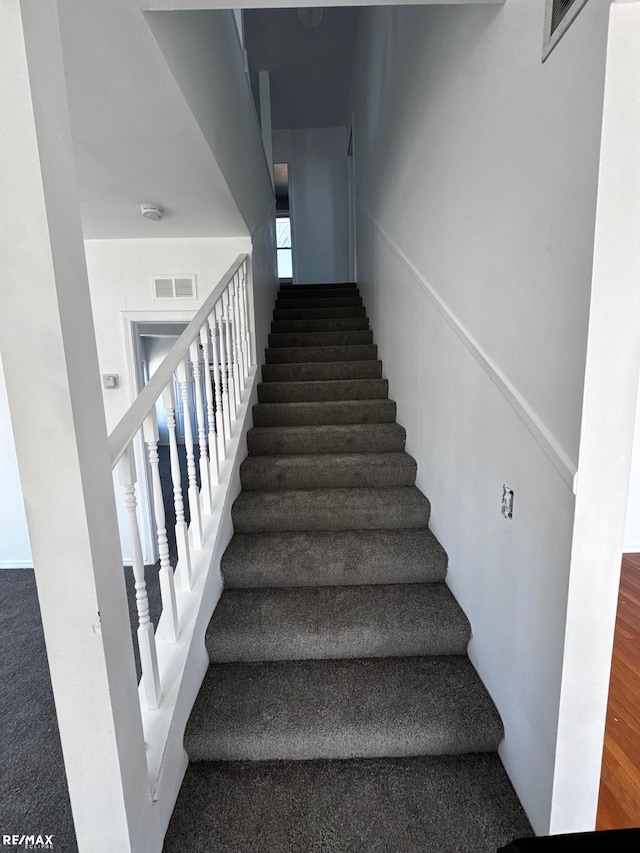 staircase with visible vents and wood finished floors