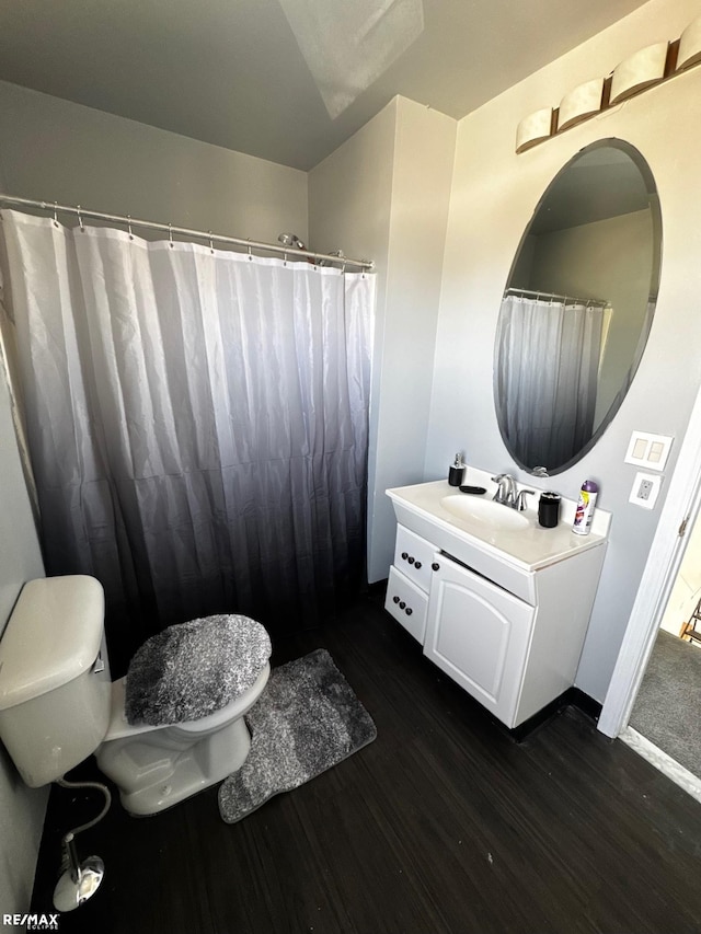 bathroom with toilet, vanity, and wood finished floors