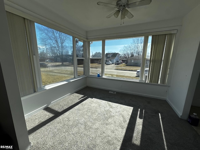 unfurnished sunroom featuring a ceiling fan